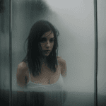 Enchanting scene of a brunette with wet hair against foggy glass, inviting viewers to explore the depth of beauty and allure.